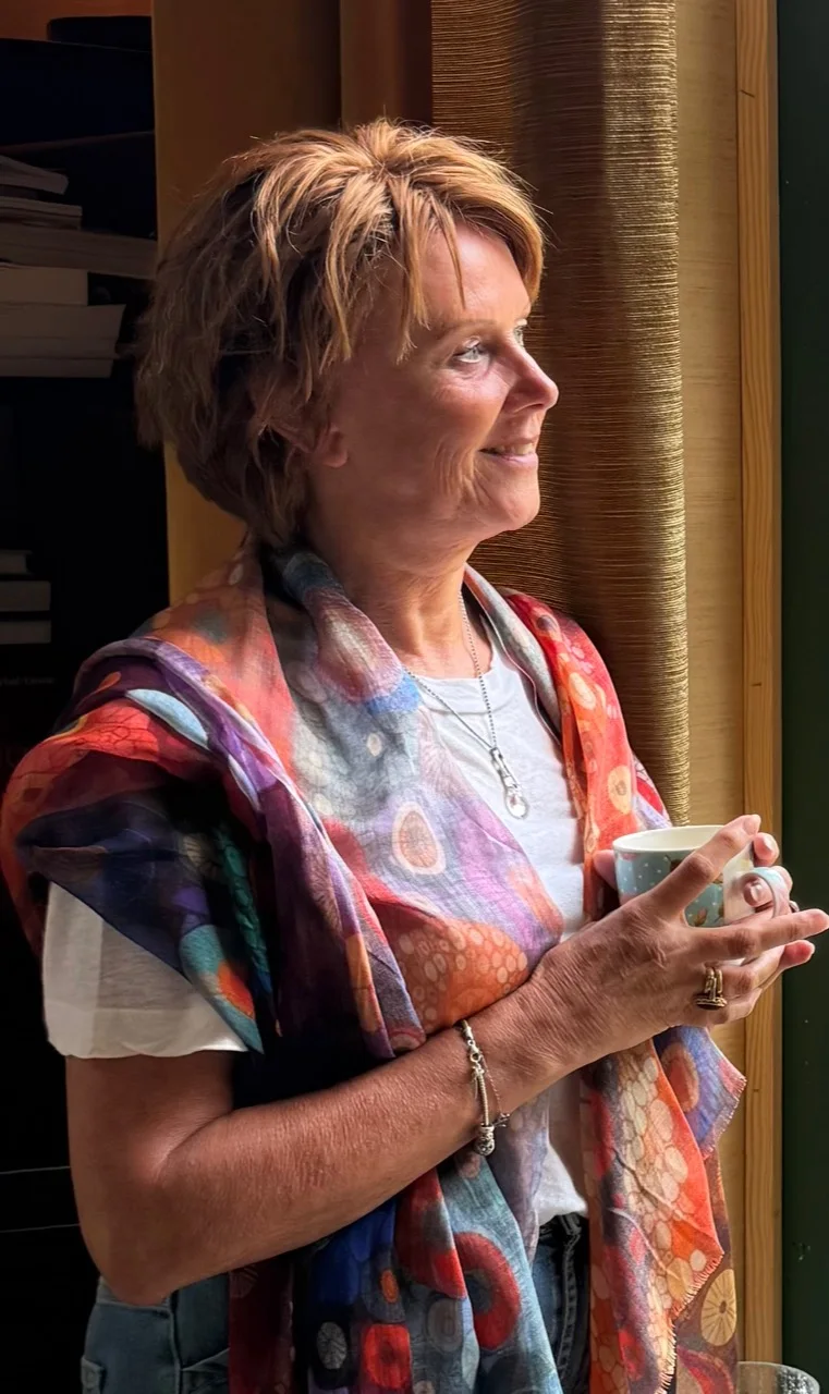 Heleen staat met een kopje in haar handen bij het raam.
