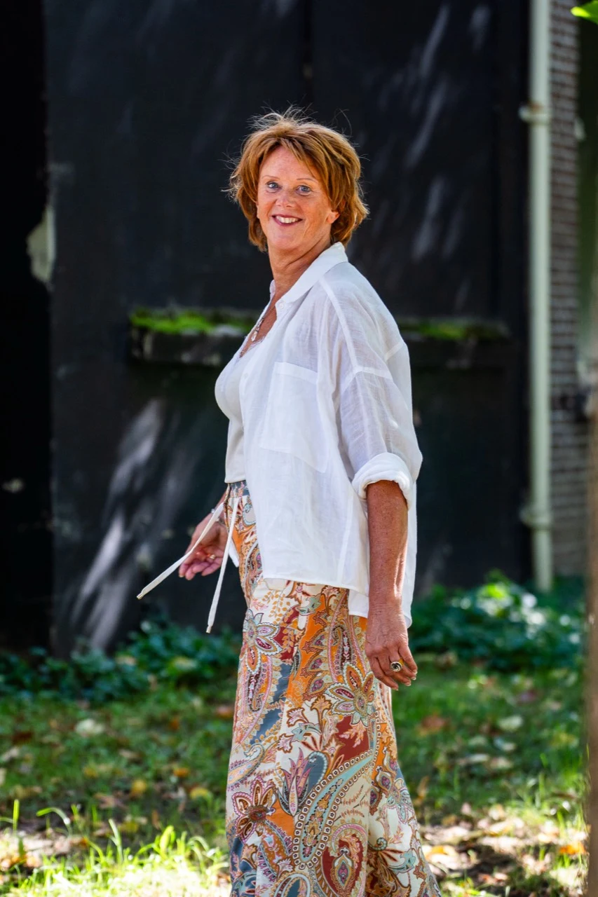 Heleen staat glimlachend buiten in het groen.
